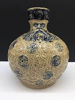 Front view showing the full jug with face mask and floral relief decoration.