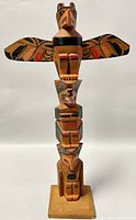 Front view of vintage Haida Native American hand carved totem pole sculpture showing eagle on top and multiple figures stacked below with painted details.