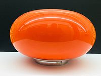 Side view showing round orange glass lamp with metal base