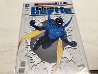 Cover of Blue Beetle #0 comic book showing Blue Beetle bursting through a wall with blue and black costume and yellow wings, The New 52 version by DC Comics.