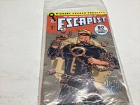 Photo showing cover of The Escapist comic book issue #1, sealed in protective plastic sleeve, depicting the main character wrapped in chains and holding a large key.