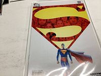Superman comic book issue #701 with large yellow Superman S symbol on red background and Superman figure in front.