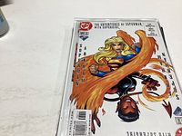 Close-up photo of The Adventures of Superman comic book cover showing Supergirl and Superman characters