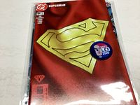 Superman comic book issue #64 front cover with metallic red background and large yellow Superman 'S' logo, sticker badge visible
