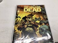 Cover of The Walking Dead Deluxe Comic Book Issue 1 showing protagonist with a rifle surrounded by zombies.