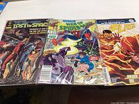 Photo showing three comic books with covers visible: Lost in Space, Web of Spider-Man, The Flash