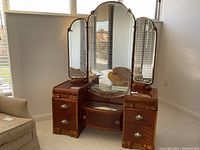 Full view of vanity showing central and side mirrors, pedestals, and curved glass-front cabinet