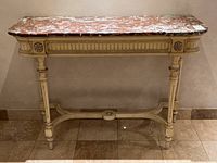 Front view of table showing marble top and carved base