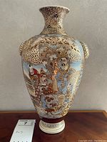 Full front view of the large Satsuma-style ceramic vase showing detailed hand-painted figures, gold gilt decoration, and creature handles near the neck.