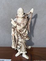 Full view of carved figurine showing posture and base.