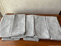 12 folded damask napkins showing the detailed woven pattern.