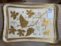 Top-down image of rectangular wood Florentine tray showing gold grape cluster and leaves design on cream background with gold border trim.