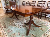 Angled view of rectangular mahogany table showing double pedestal base and carved feet