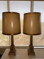 Front view of both lamps with parchment-style drum shades on table in front of window