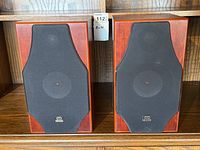 Pair of speakers with fabric grilles attached on shelf