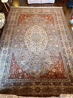 Full view of entire rug laid flat on hardwood floor showing central medallion and border layout