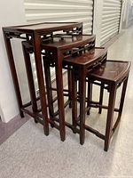 Four nested rosewood tables showing overall form, finish, and quantity.
