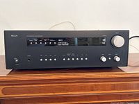 Front view of Arcam AVR200 A/V Surround Sound Receiver showing control buttons, volume knob, and digital display.