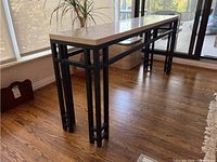 Angled view showing full profile of the table with travertine top and geometric iron base