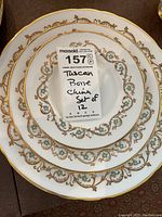 Stacked dinner, salad and bread plates with gold and turquoise scroll pattern and MaxSold sticker