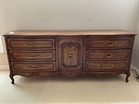 Front view of six-drawer wooden dresser with center cabinet door and brass hardware