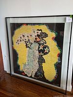 Full frontal view of framed abstract silkscreen leaning against wall on hardwood floor