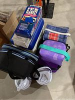 Photo of assorted coolers and lunch boxes including plastic cooler, soft side cooler, insulated lunch boxes, boxed ice blanket, and thermos cups.