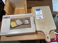 Two wooden cutting boards next to boxed set of three stainless steel breading trays by CHEFS.