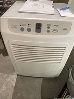 Front view of Kenmore dehumidifier with control panel and power button shown, includes blue tape note nearby.