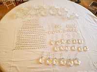 Overview of numerous loose Schonbek chandelier crystals including teardrop pendants and strands on white cloth