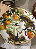 Close-up of stack of plates showing detailed dragon and peach designs with gold trim from the Williams and Sonoma New Moon collection.