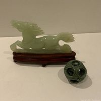 Photo of green carved stone horse statue on fitted wooden base and 4-layer carved puzzle ball showing overall condition.