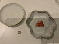 Photo showing the Hutschenreuther plate and Wedgewood bowl side by side on a table with a quarter for scale.