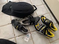 Overview of two pairs of Carnac cycling shoes and Giro black helmet case on tile floor.