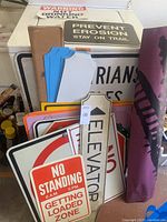 Multiple public and warning signs stacked together showing various messages and materials.