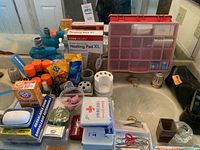 Wide shot showing various men's toiletries, mouthwash, baking soda, heating pad box, grooming accessories, and first aid kits on a bathroom counter.