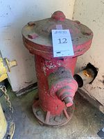 Front view of red fire hydrant showing paint chipping and dirt accumulation.