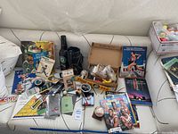 Wide angle of lot on white couch showing books, magazines, baseball items, golf gear, and ephemera.