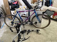 Side view of the Bianchi Peregrine mountain bike with Yakima trunk rack in front on the floor, showing full bike frame, wheels, and rack design
