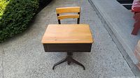 Front view of antique wooden school desk showing attached chair and metal pedestal base.