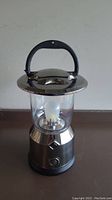 Full view of GE lantern showing silver and black design, clear protective cover, and black carrying handle.