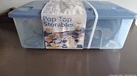 Clear plastic storage bin holding the Pop Top Storables 44-piece set with label visible and secured with white elastic band.