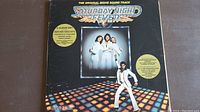 Front cover of Saturday Night Fever soundtrack with title, movie characters, and disco floor illustration.