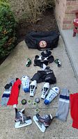Full layout of youth hockey equipment including skates, gloves, shin guards, shoulder pads, socks, tape, and bag