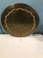 Full view of round brass serving tray showing scalloped edge and polished surface
