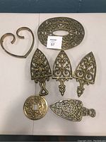 All brass trivets displayed on flat surface, showing variety of shapes and intricate designs
