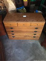 Front view of the solid wood Ethan Allen dresser showing all 5 drawers and metal handles, in a dimly lit garage setting.