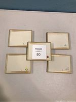 Photo showing five rectangular Japanese appetizer dishes arranged in a circular pattern with one in center. Each dish has a minimal floral design and gold rim.