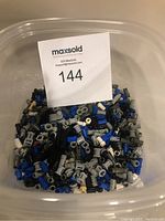 Photo of clear plastic container filled with assorted small Lego and Lego Robotics parts in grey, blue, black and tan.