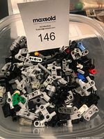 Photo showing assorted Lego Technic and Robotics connectors, pins, and parts in a container, featuring mostly gray, black, and blue pieces.